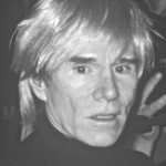 Black-and-white photo of a person with light-colored, messy hair, wearing a dark turtleneck and looking directly at the camera with a neutral expression, reminiscent of iconic Andy Warhol portraits.