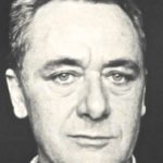Black-and-white close-up portrait of a middle-aged man with short, dark hair, a serious expression, and light-colored eyes, facing the camera against a plain background—reminiscent of Gerhard Richter's striking photographic style.