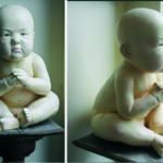 A realistic sculpture of a seated baby with clasped hands, reminiscent of STEPHAN BALKENHOL ATLAS, is displayed on a dark pedestal near a light-colored wall and window, viewed from both the front and side.