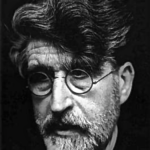 Schwarz-Weiß-Porträt eines älteren Mannes mit dichtem, gewelltem Haar, Vollbart und runder Brille. Er erinnert an den Stil von Valerio Adami und blickt mit ernster Miene leicht nach unten vor einem dunklen Hintergrund.